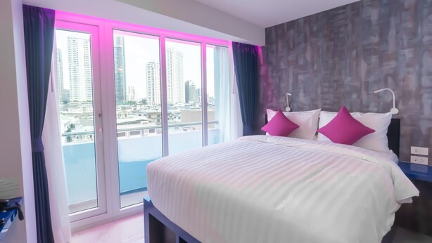 A modern hotel room with a large bed, a view of the city through floor-to-ceiling windows, and a balcony. - Spark Hotel (Bangkok)