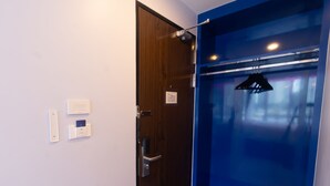 A room with a wooden door, a blue wall, and a hanging garment rack. - Spark Hotel (Bangkok)