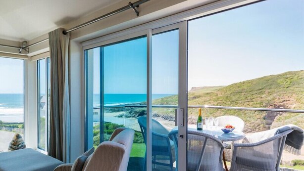 A balcony with a table, chairs, and a bottle of champagne.
