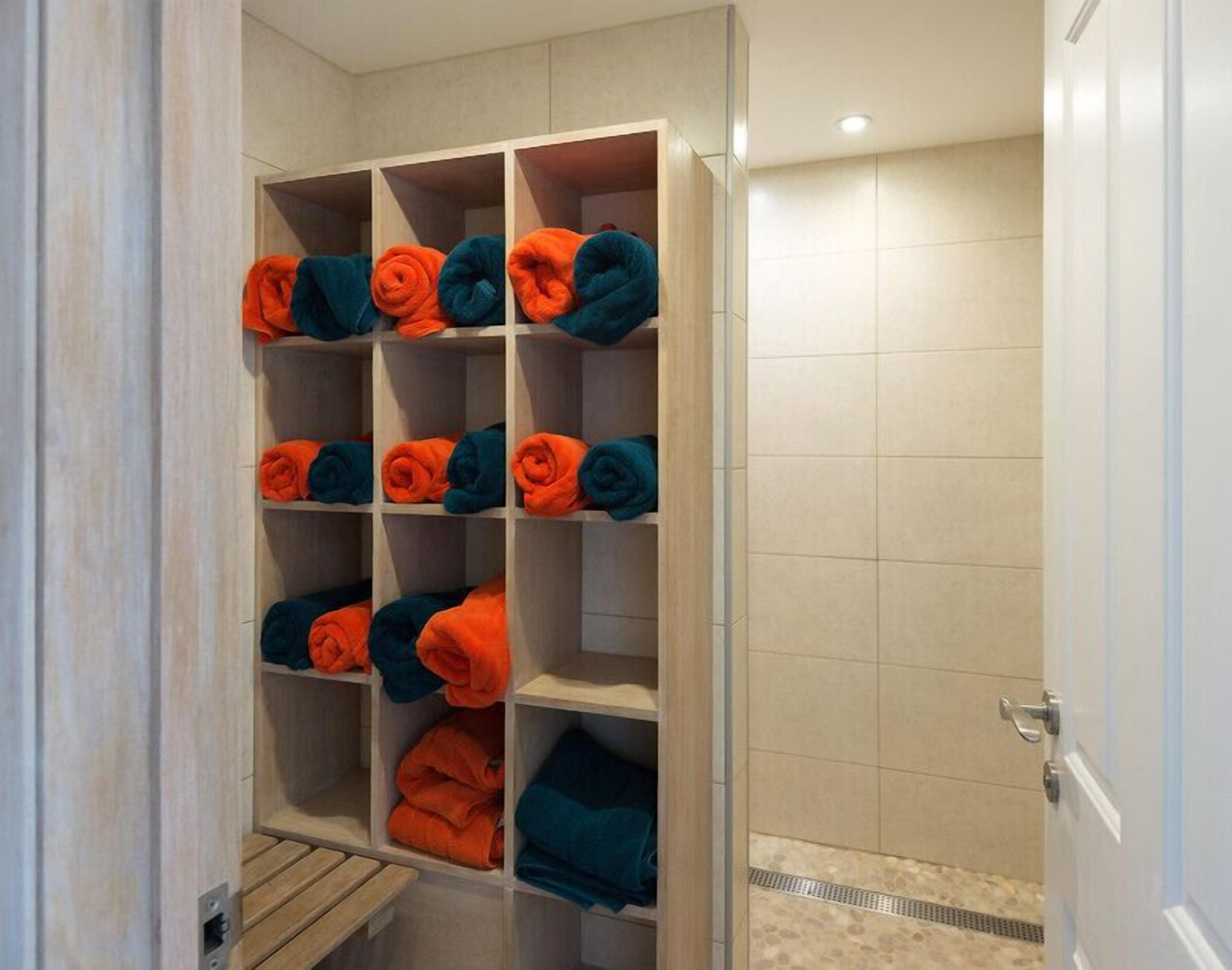 A hotel bathroom with a wooden vanity, a towel rack with neatly folded towels, and a shower area.