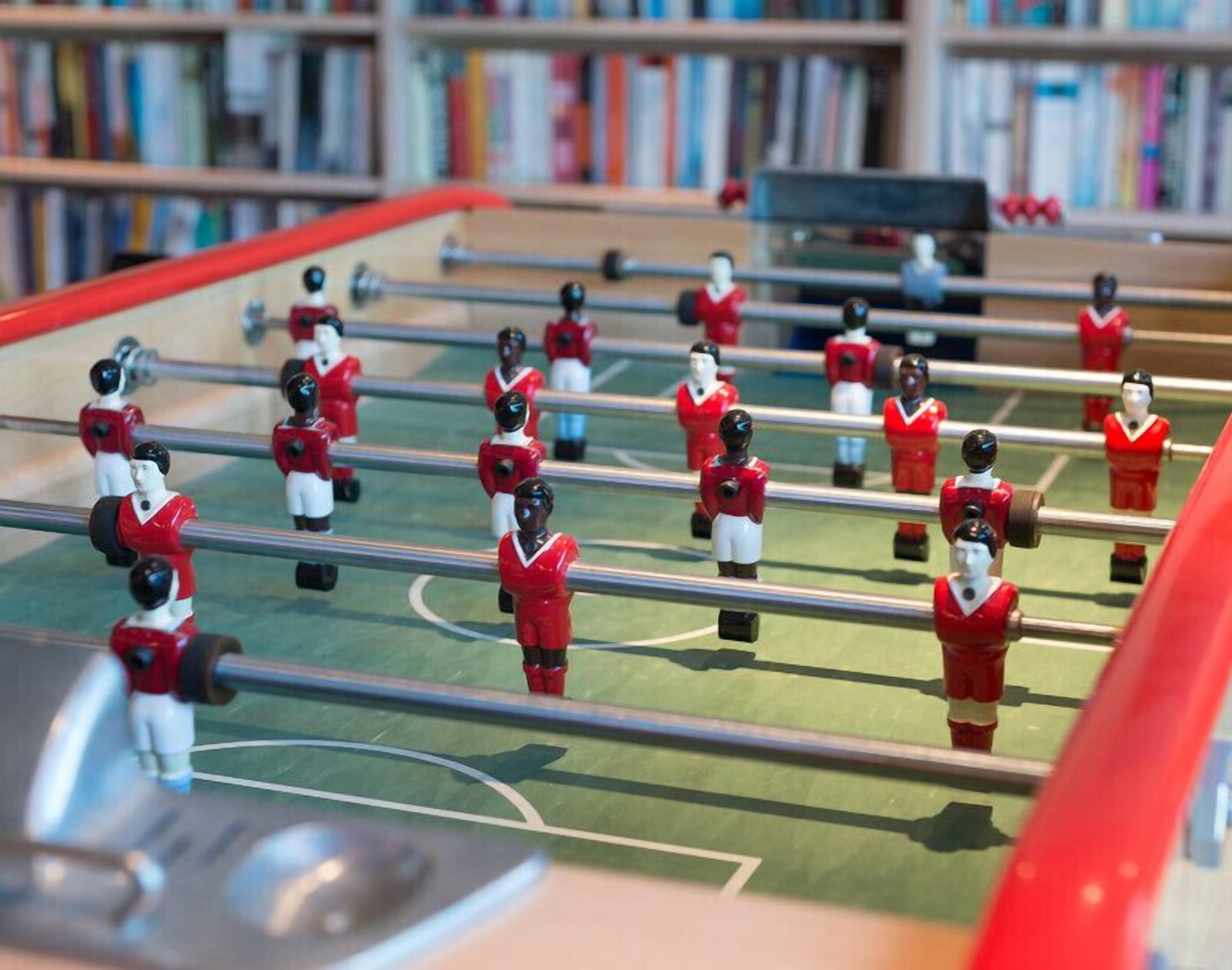 Une table de baby-foot avec des joueurs portant des maillots rouges.