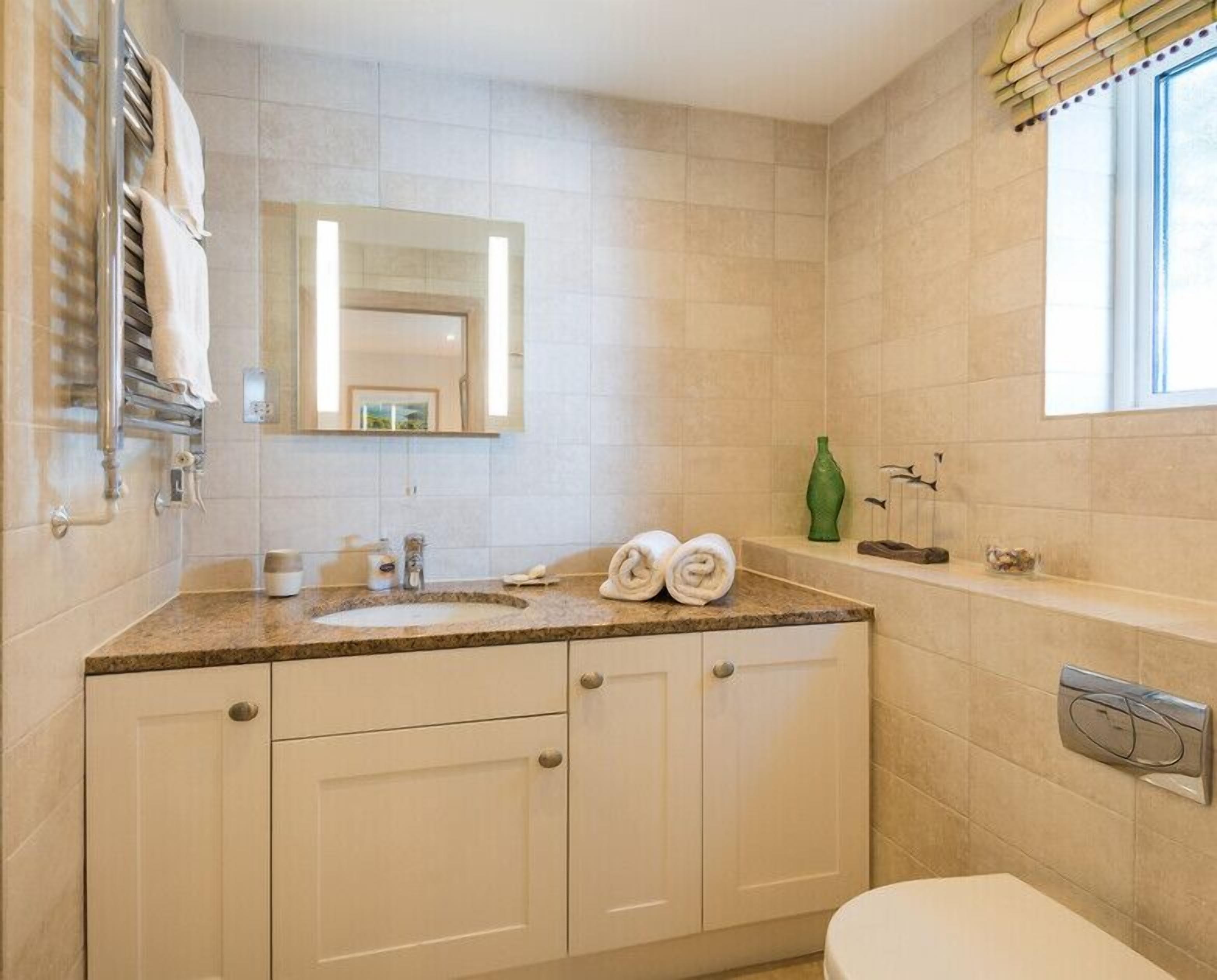 A bathroom with a sink, mirror, towel rack, and toilet.