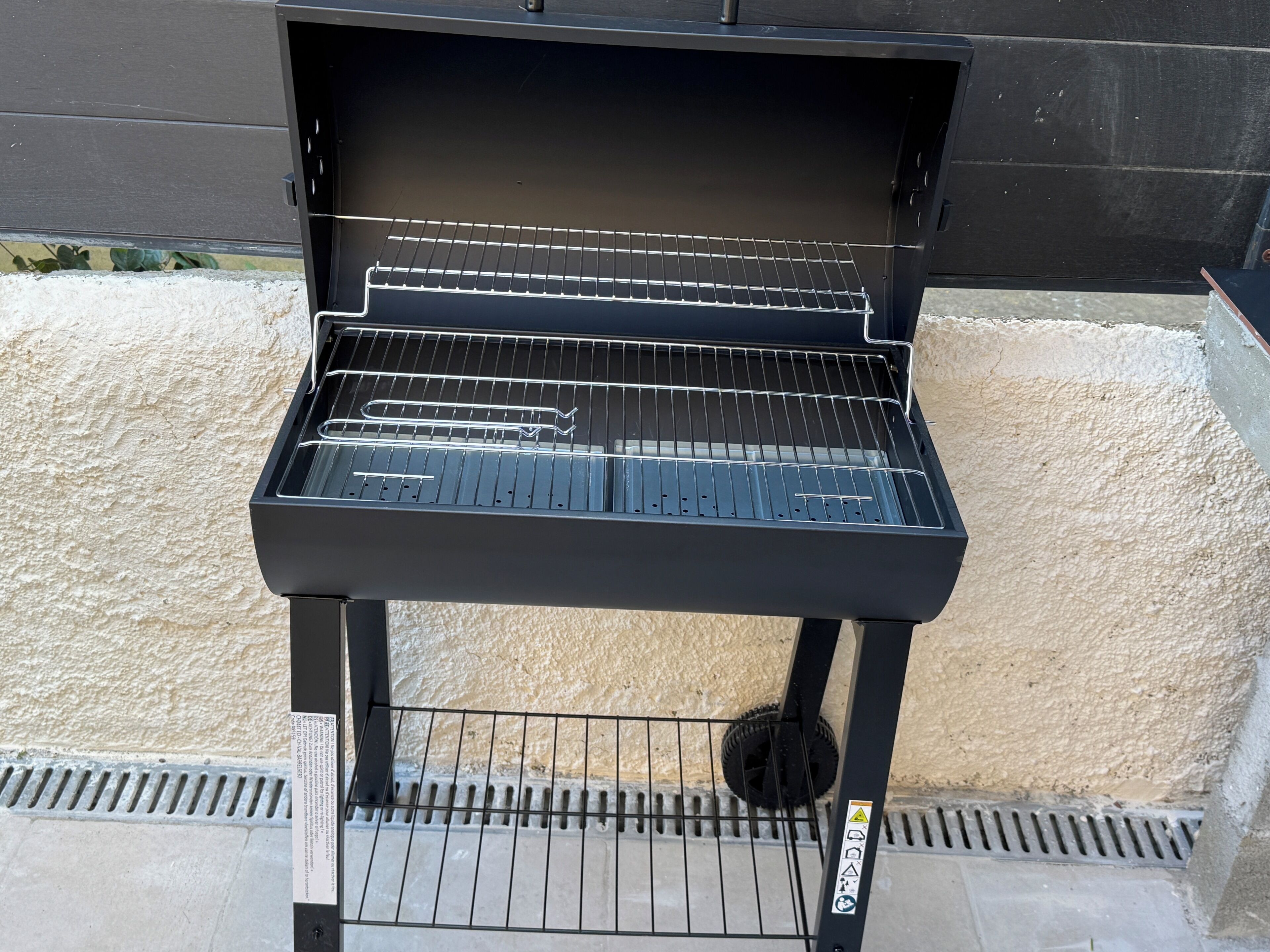 Un barbecue doté d’une grille en métal, d’un panneau de commande et d’une ouverture de ventilation située en bas.