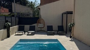 A rectangular swimming pool with clear blue water, surrounded by a tiled patio with lounge chairs and a hanging chair. - House 14 pers Heated pool center Valras-Plage (Valras-Plage)