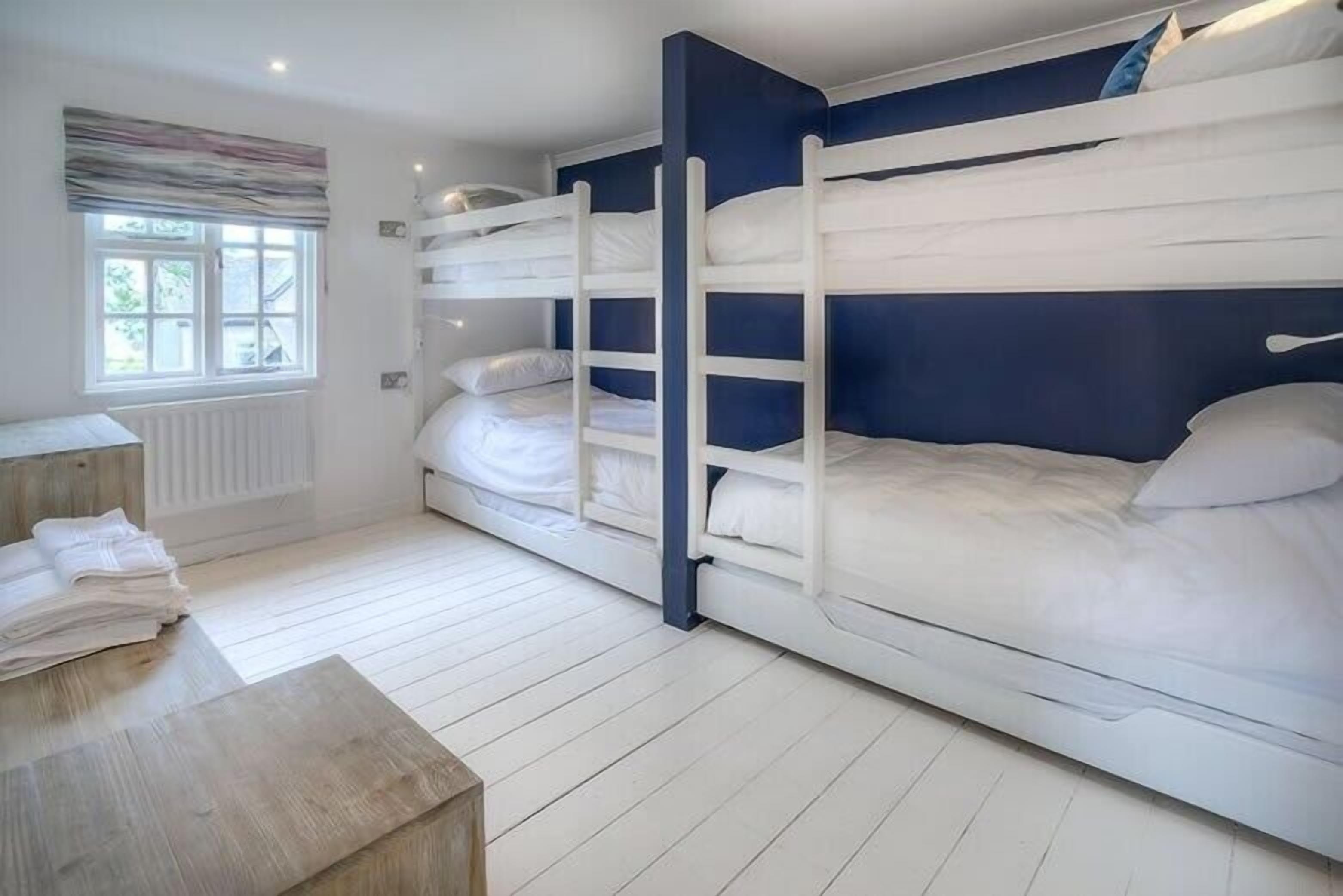 Une pièce avec des lits superposés, un radiateur, une fenêtre et une table en bois.