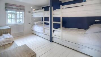 A room with bunk beds, a radiator, a window, and a wooden table.
