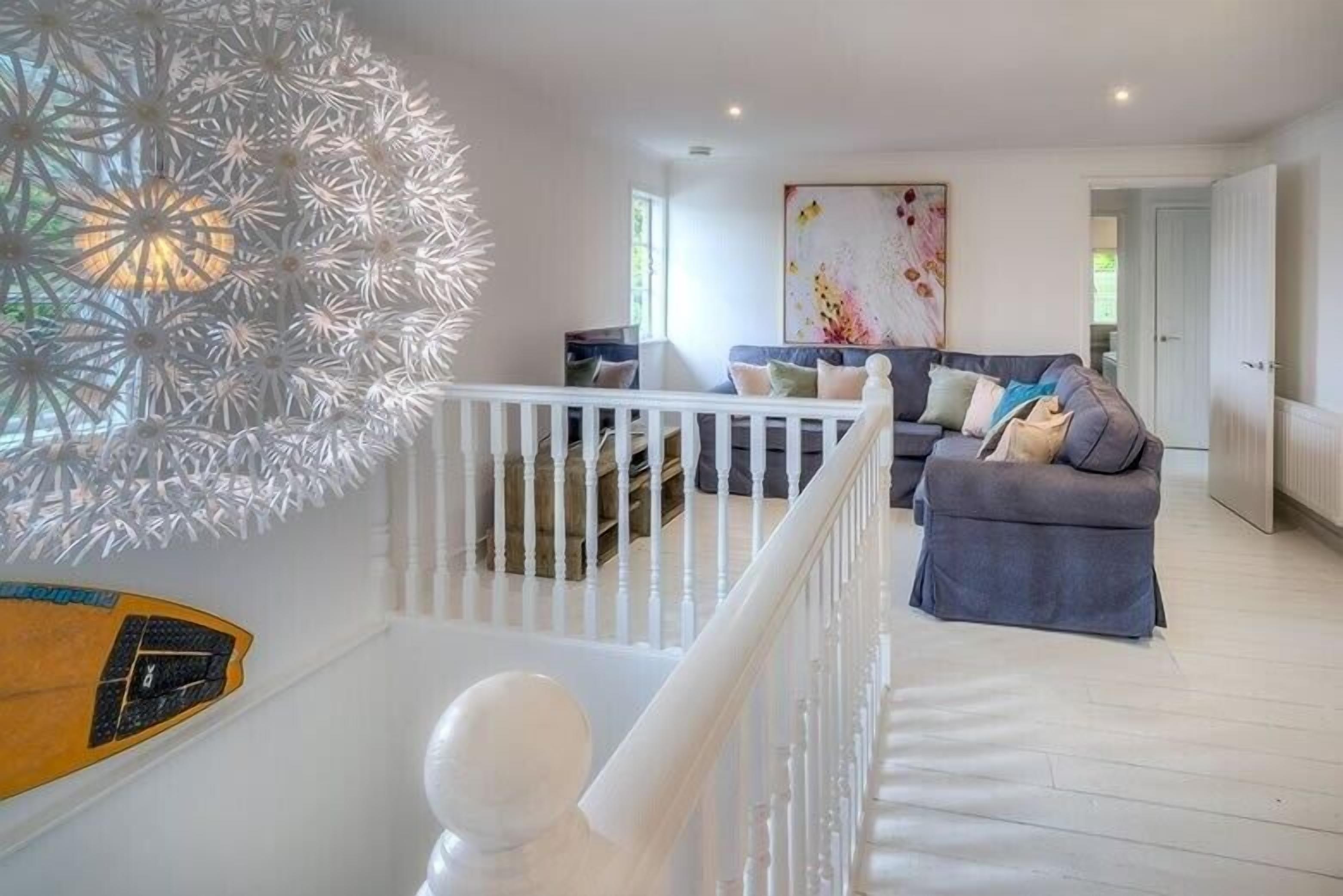 A modern living room with a grey sofa, a white railing, and a decorative wall piece.