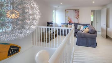 A modern living room with a grey sofa, a white railing, and a decorative wall piece.