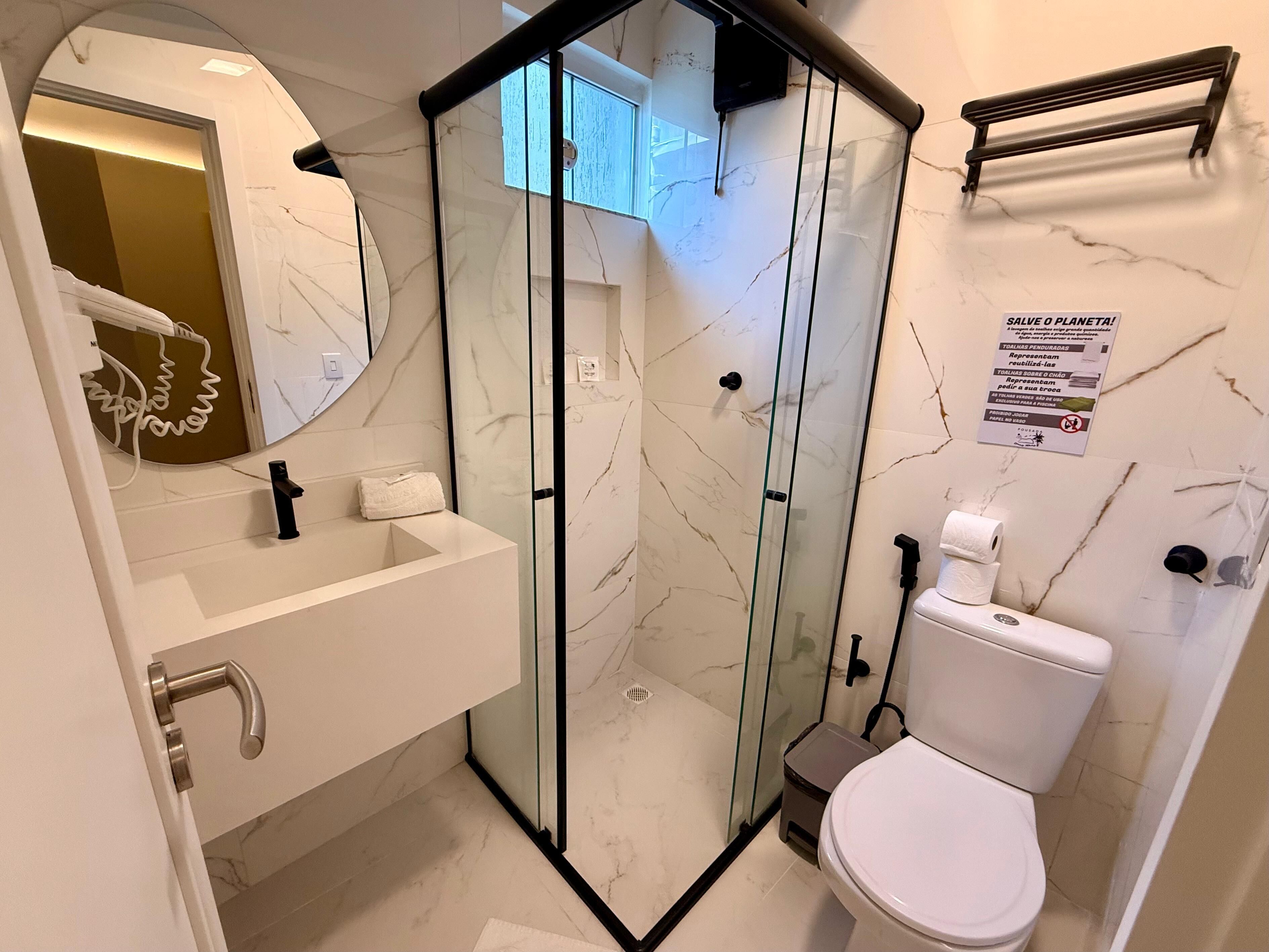 A modern bathroom with a glass-enclosed shower, a white sink with a towel, and a toilet.