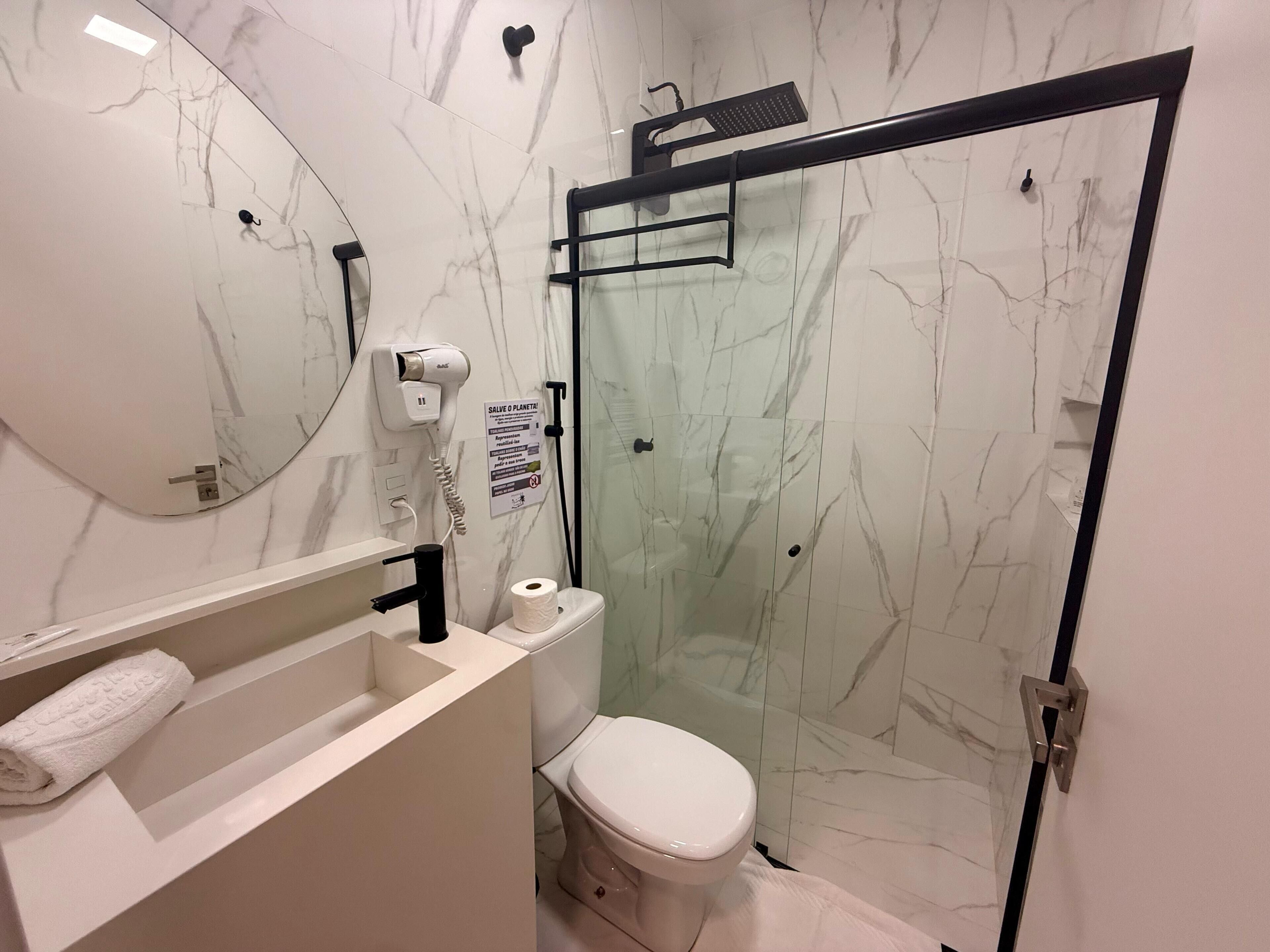 Un baño moderno con inodoro, lavabo y ducha con mampara de vidrio.