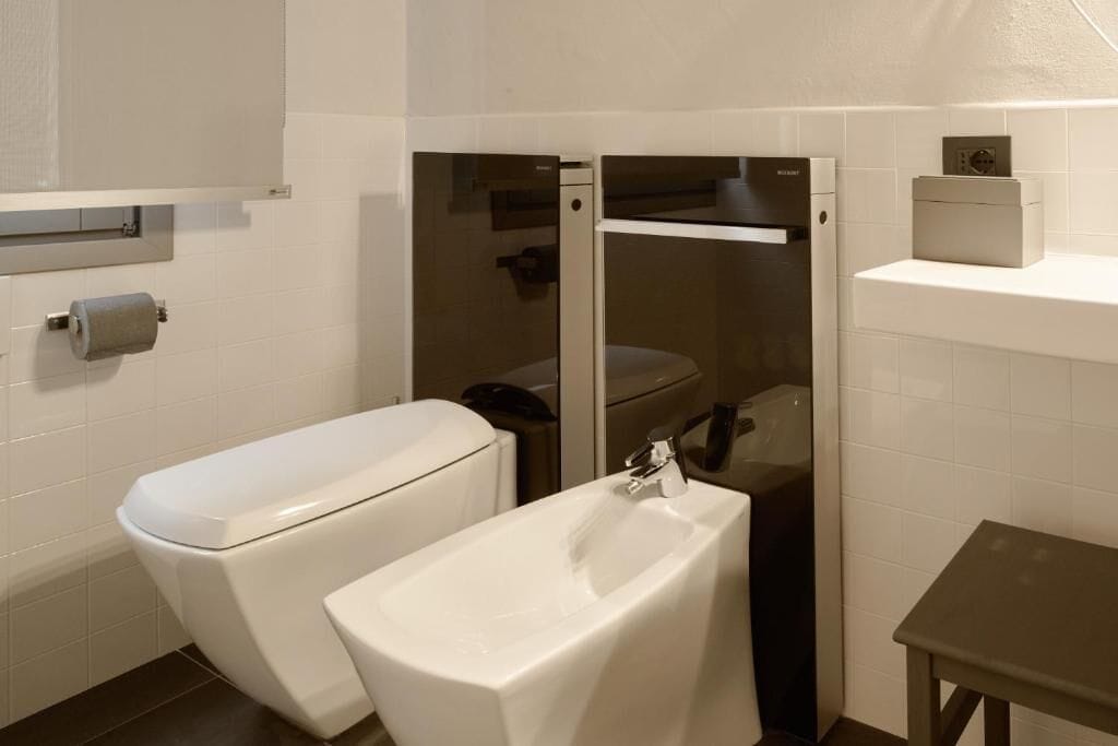 A modern bathroom with a toilet, bidet, and sink.