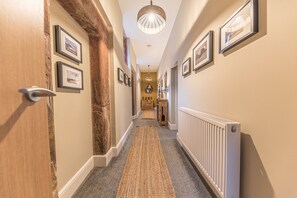 Stunning hallway with framed artwork, a door, and a radiator, leading to a room with a door at the end.