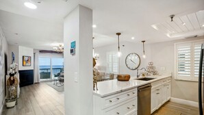 Una cocina moderna con armarios blancos, una isla grande y vistas al exterior.