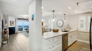 A modern kitchen with white cabinetry, a large island, and a view to the outside.