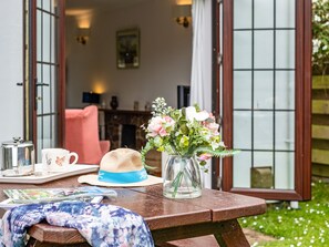A wooden table with a hat, a vase with flowers, a tray with a teapot and cups, and a magazine. - Hazelhurst (Wadebridge)