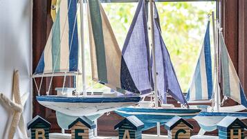 A model sailboat collection on a windowsill with alphabet blocks labeled B, E, A, C, and H.