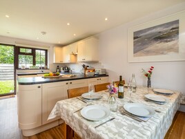A modern kitchen with white cabinets, a black countertop, and a dining area set for four with a table set for a meal.