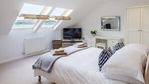 A bedroom with a skylight, a TV, a dresser, and a wardrobe. - Upper Deck (Wadebridge)
