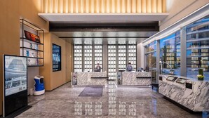 A modern hotel lobby with marble flooring, a reception desk, and a large window with a city view. - Novotel Shanghai Wanyuan (Shanghai)