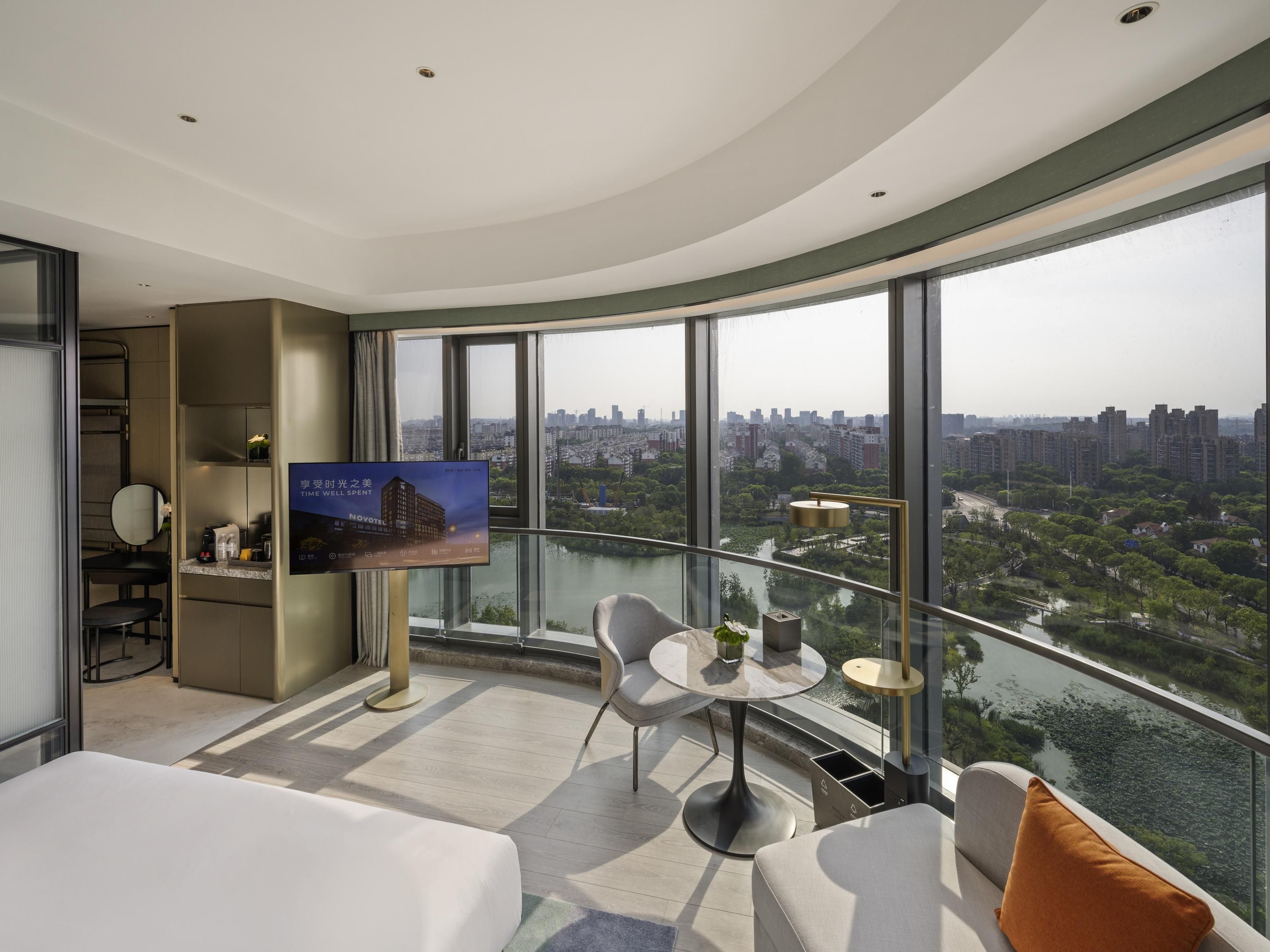 Una habitación de hotel moderna con techo curvo, un amplio ventanal panorámico, cama, una mesita redonda y un rincón de descanso.