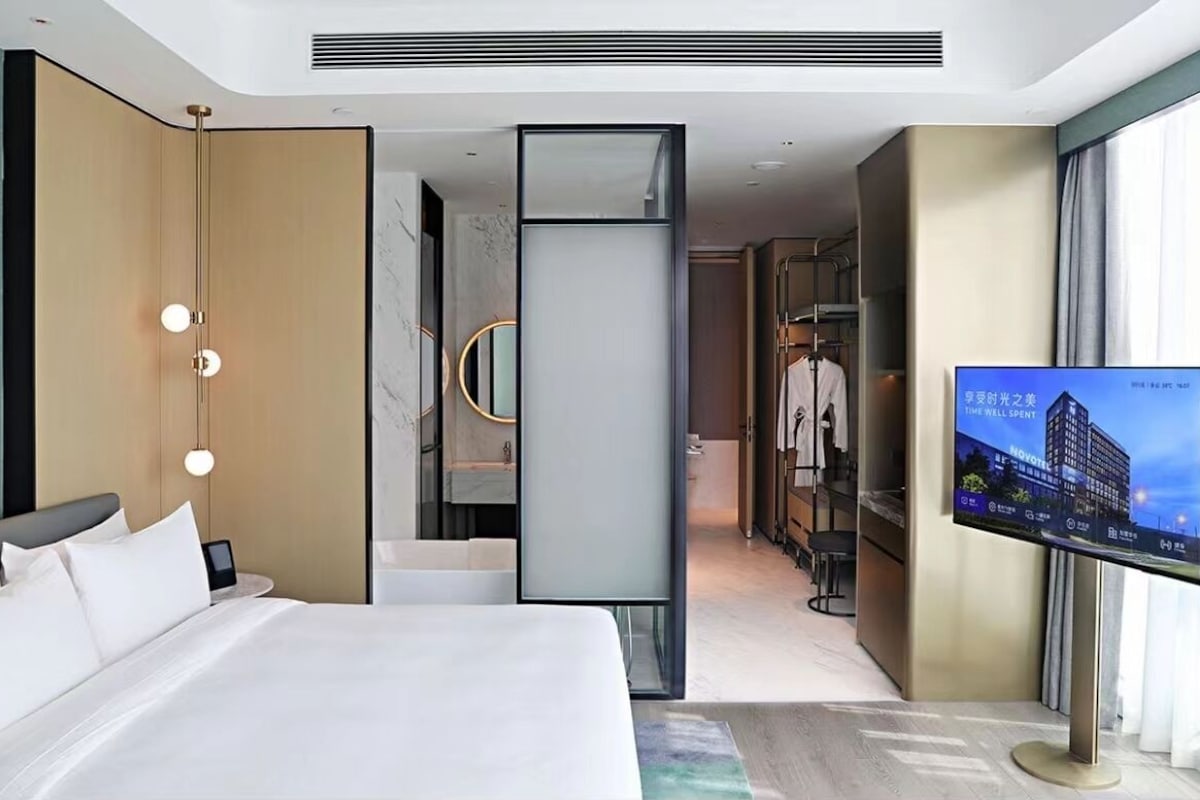 Quarto de hotel moderno com uma cama grande, televisão, guarda-roupa e closet.