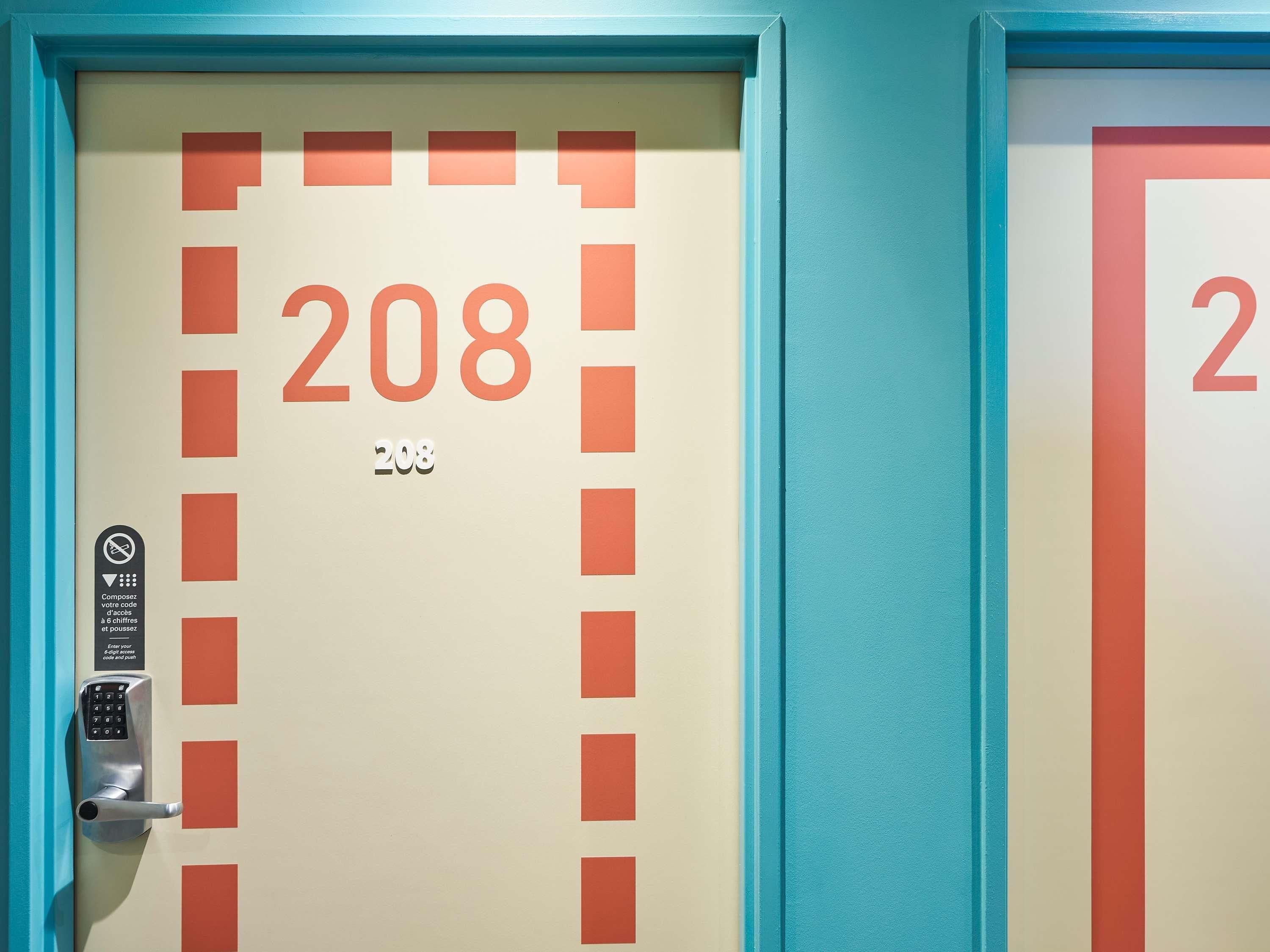 A hotel room door with the number 208, a keypad lock, and a sign indicating a 6-digit code and push button.