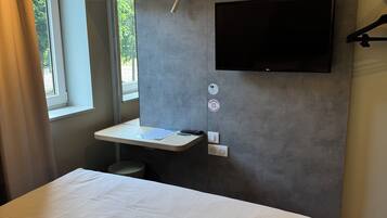 Une chambre d’hôtel moderne avec un grand lit, un bureau doté d’un téléviseur à écran plat et une fenêtre avec des rideaux.