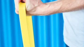 Una persona sostiene un objeto amarillo sobre un fondo azul.
