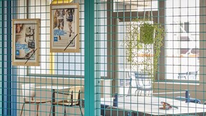 A room with a table, chairs, a window with a view, and a poster on the wall. - Ibis Budget Nancy Laxou (Laxou)
