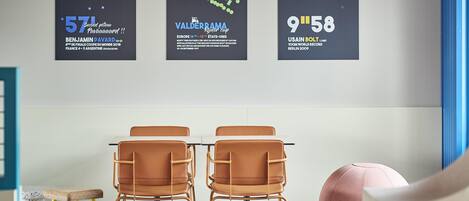 Una habitación moderna con dos sillas marrones, una mesa y un cartel grande en la pared.