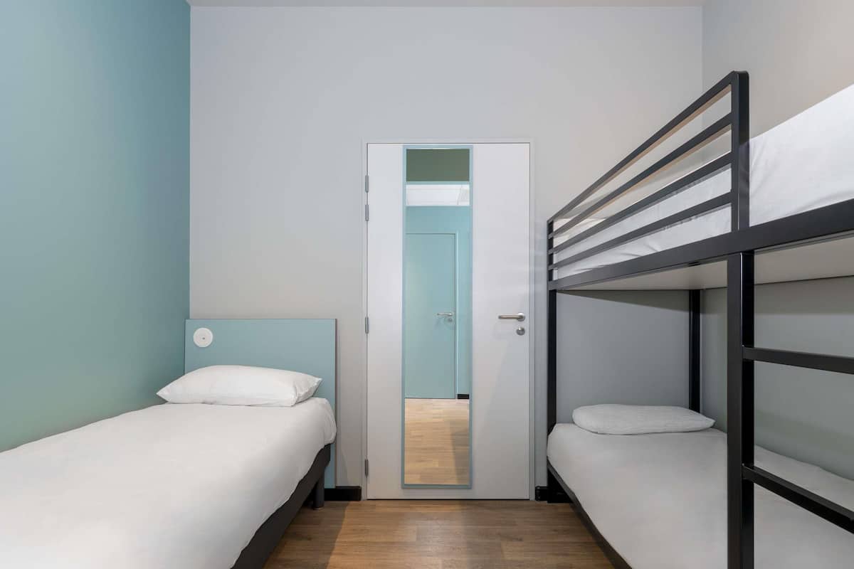A room with two single beds, a door, and a bunk bed.