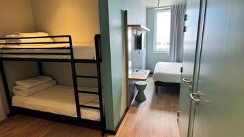 A compact room with bunk beds, a small desk, a wardrobe, and a window.