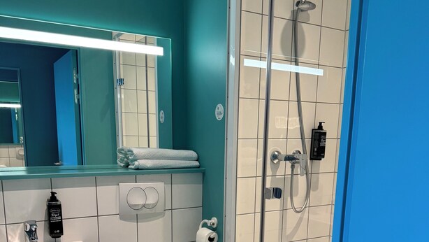 A modern bathroom with a glass-enclosed shower, a white sink, and a toilet. - Ibis Budget Nancy Laxou (Laxou)