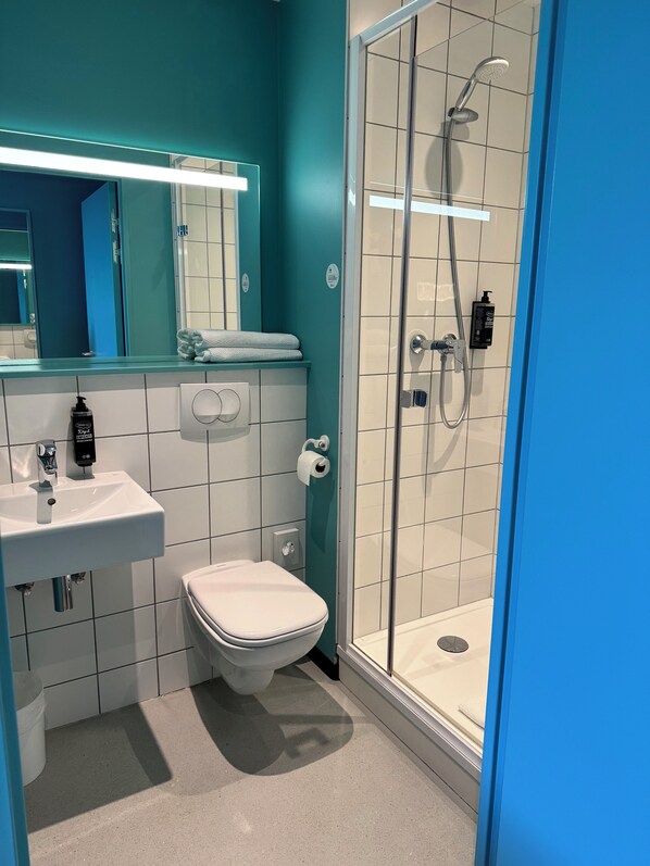 Un baño moderno con ducha de mampara de vidrio, un lavabo blanco y un inodoro.