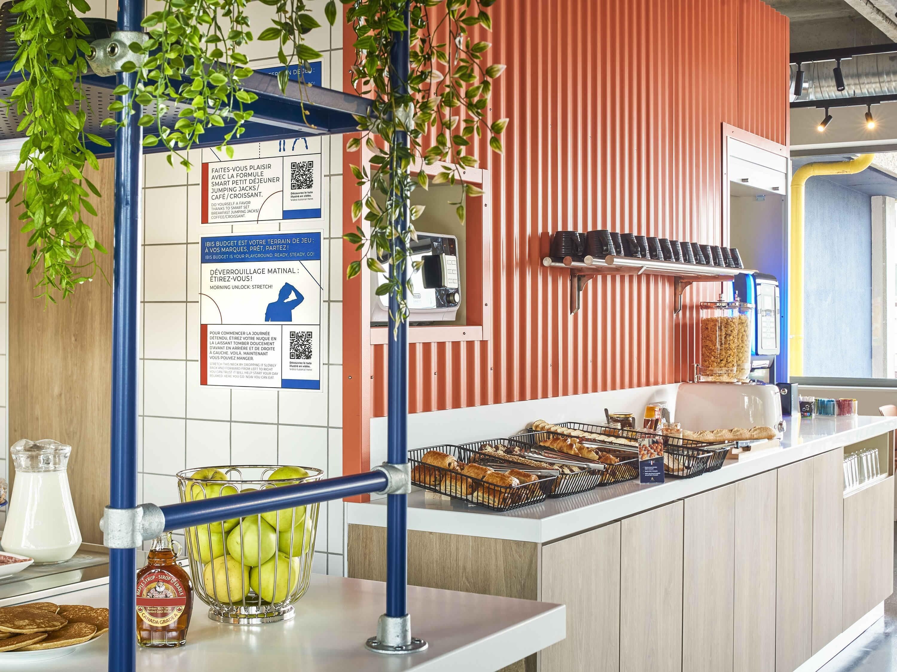 A breakfast bar with a variety of pastries, a coffee machine, and a bottle of syrup.