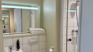 A modern bathroom with a toilet, sink, and shower. - Ibis Budget Nancy Laxou (Laxou)