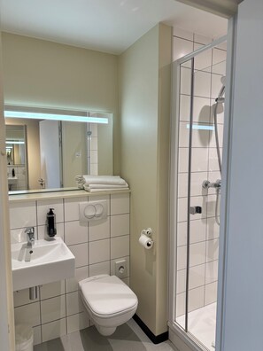 Un baño moderno con inodoro, lavabo y ducha.