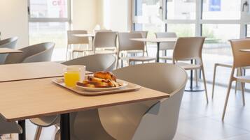 Un moderno comedor con una mesa lista para el desayuno, incluyendo tostadas y un vaso de jugo de naranja.