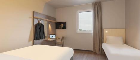 A hotel room with two beds, a desk with a laptop, a TV, and a window with curtains.