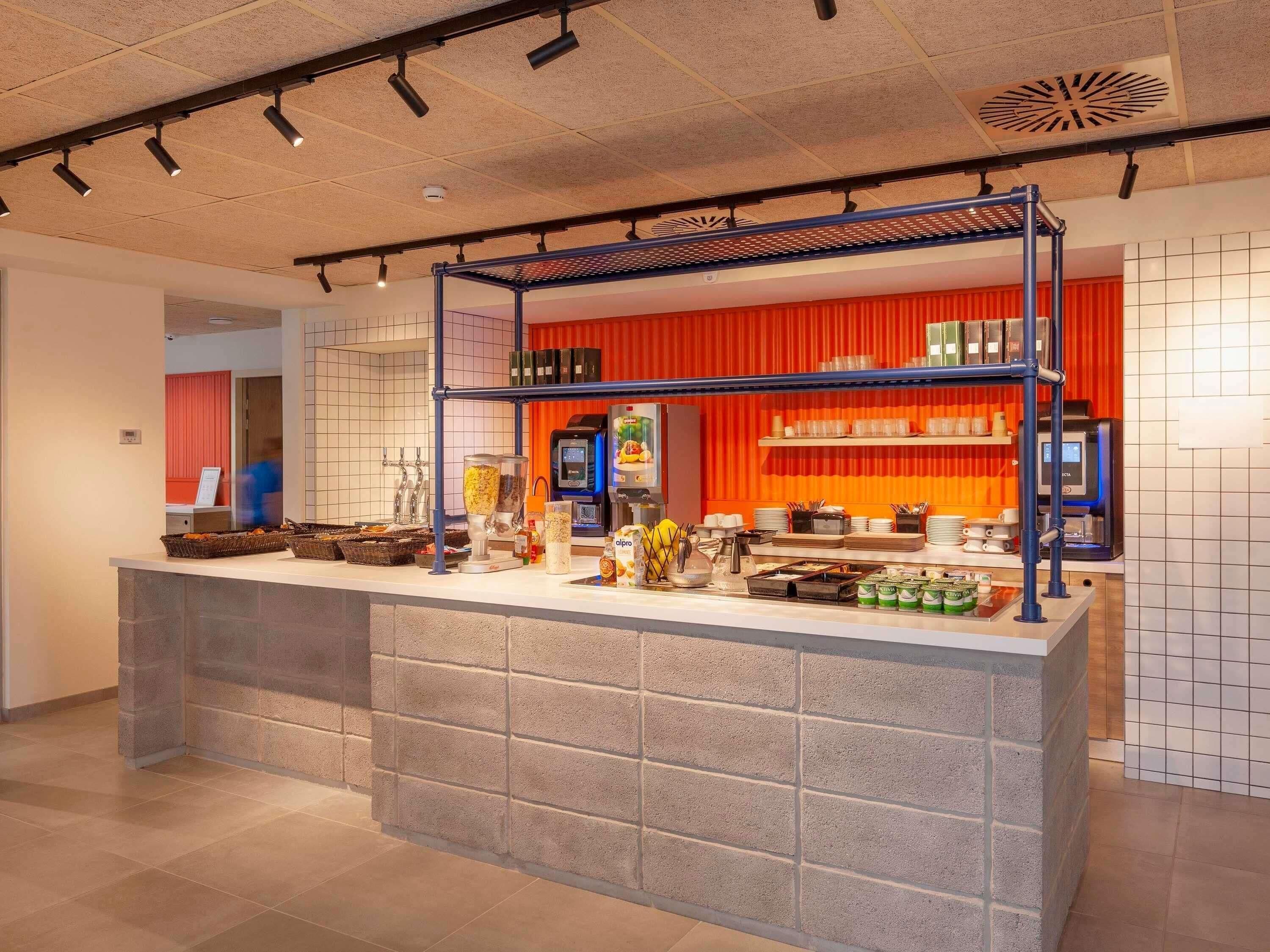 Una cocina moderna con una isla central, un muro de acento rojo e iluminación empotrada en el techo.