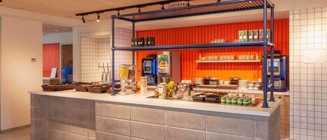 Una cocina moderna con una isla central, un muro de acento rojo e iluminación empotrada en el techo.