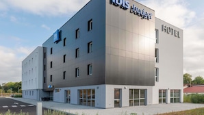A modern hotel building with a flat roof, multiple windows, and a sign that reads "ibis budget HOTEL".