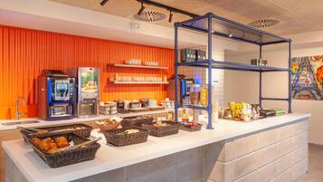 Een ontbijtbuffet met koffieautomaten, schalen vol gebak en planken met toevoegingen.