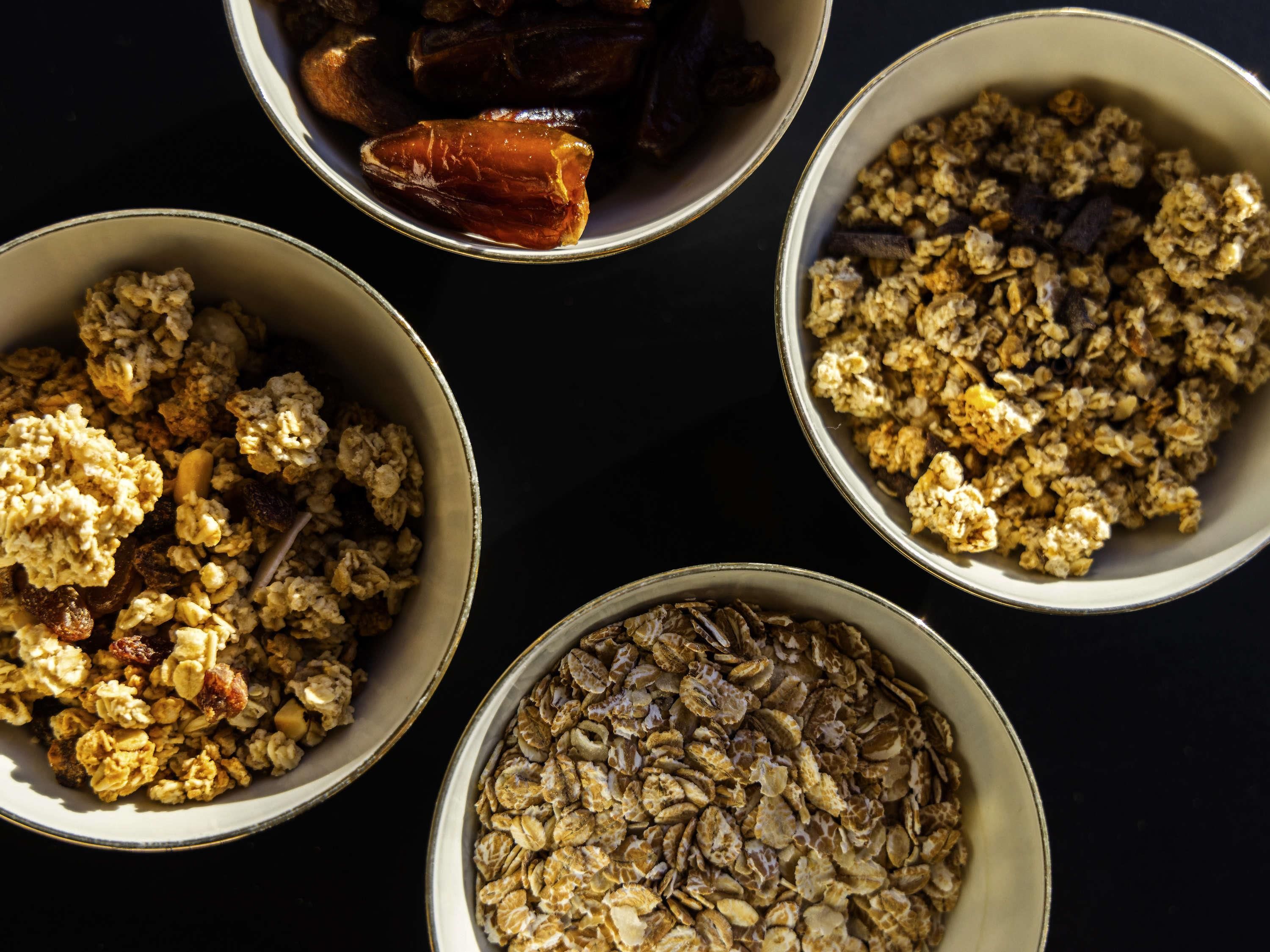 Four bowls of granola with various toppings.