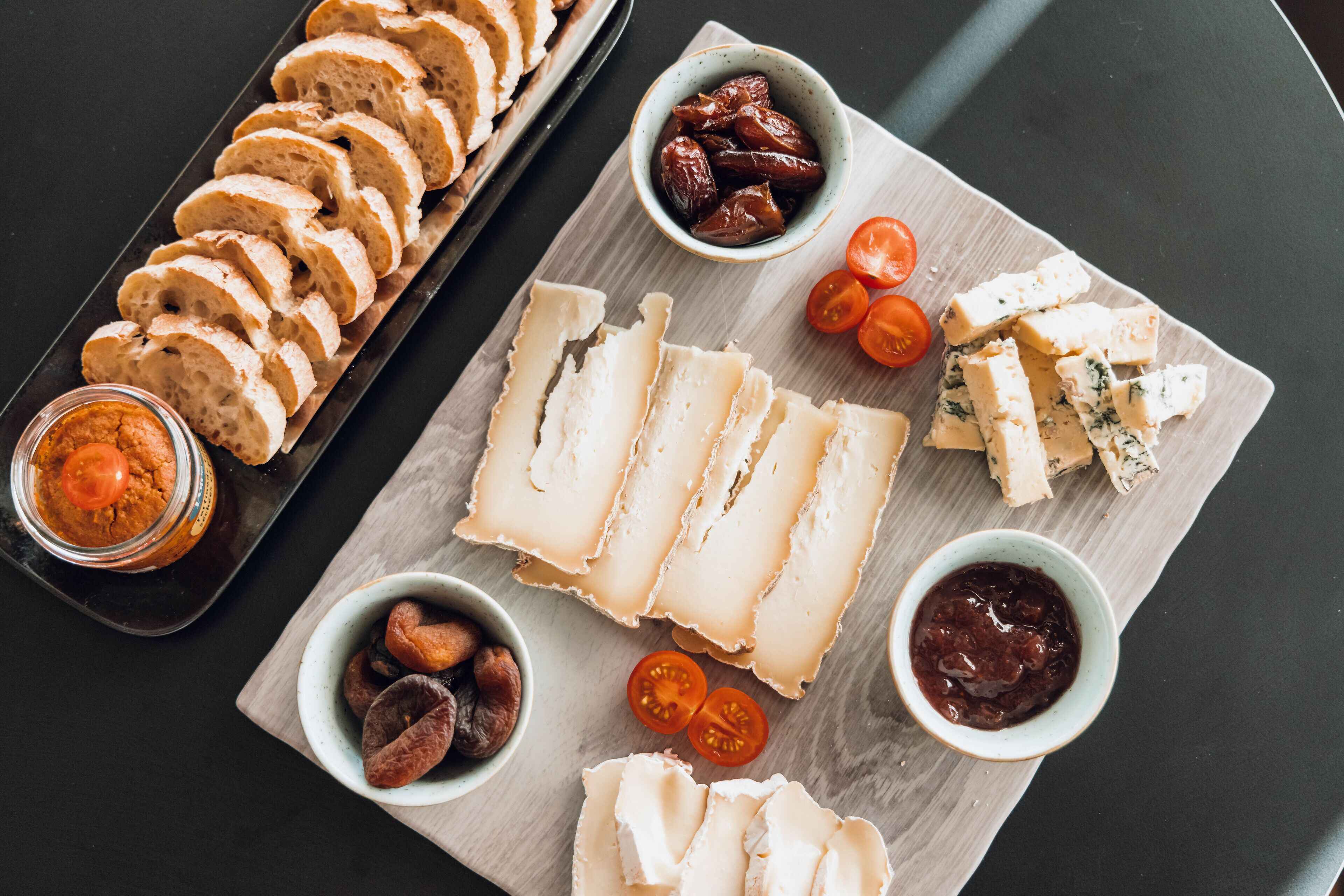 A variety of cheeses and accompaniments on a wooden board.