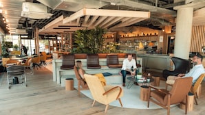 Un espace de détente moderne, doté de meubles en bois, d’un bar et de grandes fenêtres.
