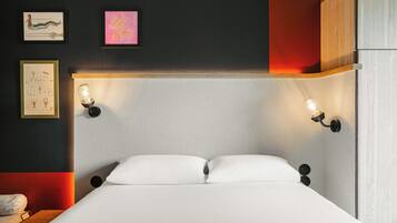 A modern bedroom with a large bed, two wall-mounted reading lights, and artwork on the wall.