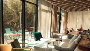 Un intérieur moderne avec de grandes fenêtres, un plafond en bois et différents types de sièges, notamment un canapé et des fauteuils.