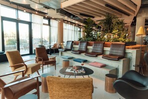 Ein stilvoller Lounge-Bereich mit Ledersitzmöbeln, einem Couchtisch und einer großen Pflanze.