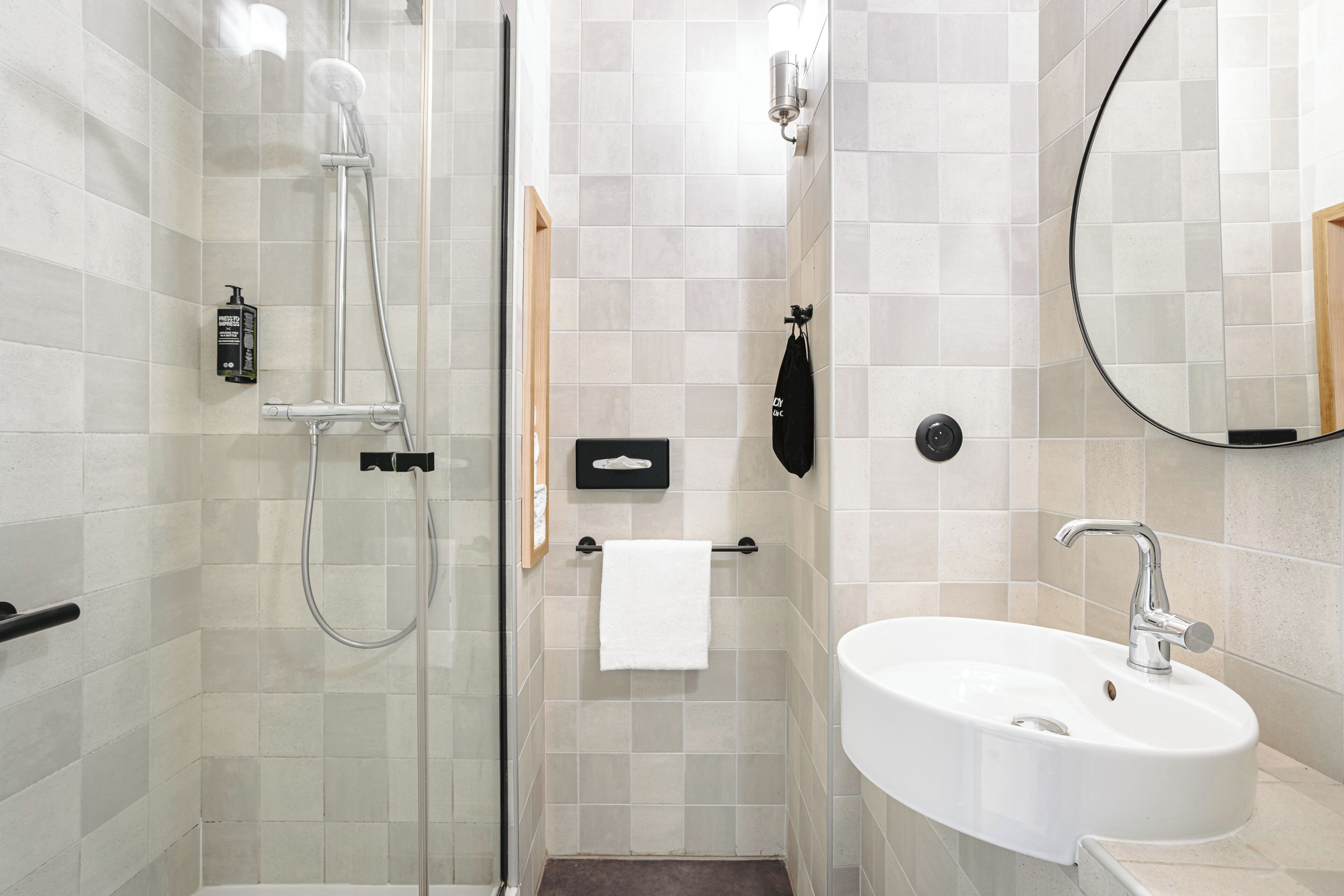 Un bany modern amb plat de dutxa de vidre, un lavabo blanc i un mirall.